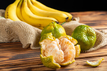Oranges and Bananas, oranges and bananas positioned on a rustic wooden surface and dark background, selective focus.