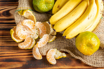 Oranges and Bananas, oranges and bananas positioned on a rustic wooden surface and dark background, selective focus.