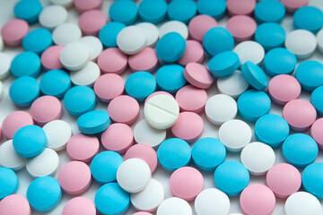 White, blue and pink tablets scattering on the table
