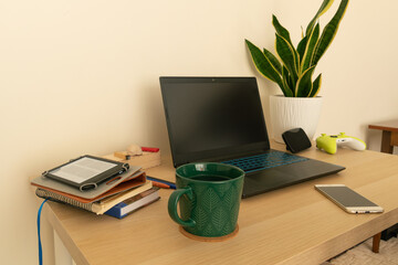 Fototapeta premium Home workspace with various items such as laptop, cup, potted plant, etc. Work from home, remote work.