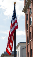 Fototapeta premium American flag waving in the wind against a blue sky backdrop outdoors