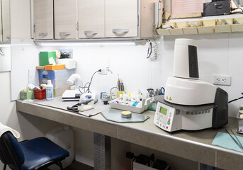 Dental laboratory workbench equipped with furnace, tools, and materials for manufacturing crowns, bridges, and other dental prosthetics. Dental technology workspace.