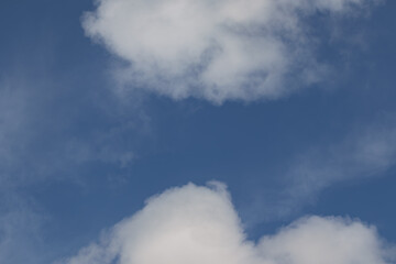 White puffy cumulus clouds in a blue sky background texture.