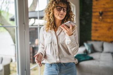 woman send voice mail and stand by the window in bright living room