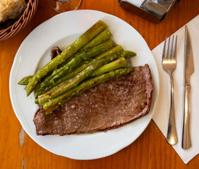 Delicious fried beef loin served with vegetable garnish of roasted asparagus