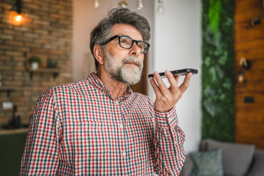 happy senior man use mobile phone for send voice message at home