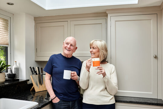 Coffee, smile and senior couple in kitchen at home together in the morning for conversation, love and healthy connection. Tea cup, happy and elderly man and woman enjoying drink in mug in retirement.