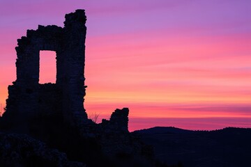 Obraz premium Crumbling Castle Walls and Clock Tower at Purple Sunset in Rural Spain