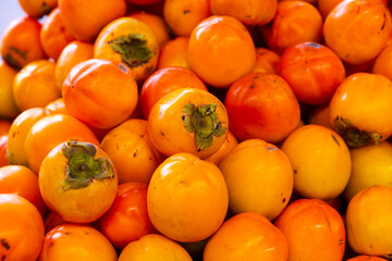 Many of fresh persimmons on the counter, put up for sale in the supermarket. Close-up image