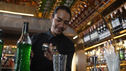 Asian bartender pouring mixed cocktail juice liqueur all ingredient into sliver shaker alcohol drink, making special advertisement creative tasty, focused refreshing showcase at bar luxury. Vinosity.