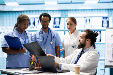 Group of healthcare workers analyzing diagnostic data and planning treatment in a modern private clinic, emphasizing collaboration. Coordinating recovery plans and discussing recent test results.