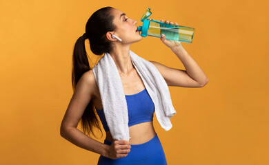 Fitness And Healthy Lifestyle Concept. Portrait of sporty young woman drinking mineral water from...