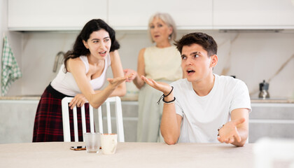 Elderly woman and young girl swear at guy. Mom and older sister scold young guy for unsuccessful studies at university. Complex intergenerational relationships