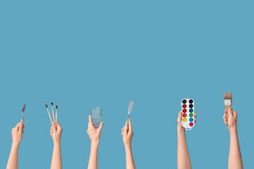 Female hands with artist's supplies on blue background