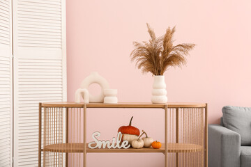 Wooden table with pumpkins and pampas grass in interior of living room