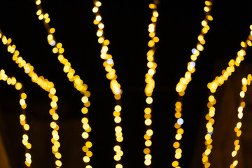 Vibrant display of golden string lights in defocused pattern, glowing against the night sky. The blurred lights create warm, abstract bokeh effect