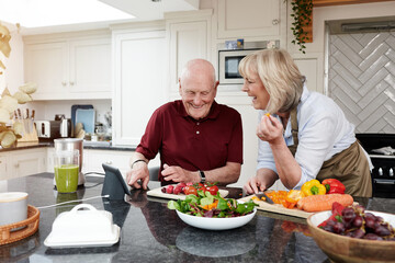 Internet, cooking and senior couple with a tablet, online recipe and digital app with instructions, vegetables or home. Kitchen, elderly man or old woman with technology, conversation or healthy food