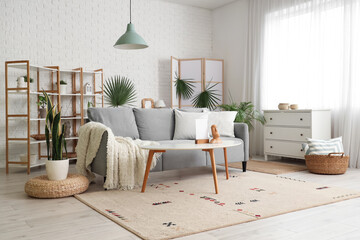 Interior of living room with sofa, folding screen and plants