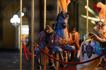 Vintage carousel horse at nighttime with illuminated background.