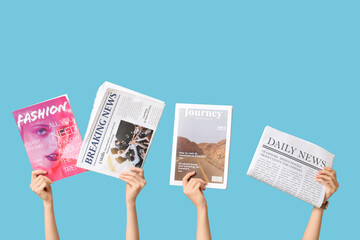 Female hands with different magazines and newspapers on blue background