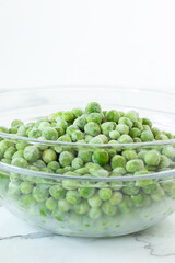 Frozen green peas in a bowl with white background. Copy space. Selective focus.