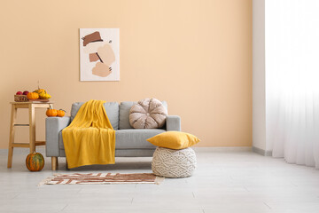 Interior of cozy living room with sofa, pouf and pumpkins