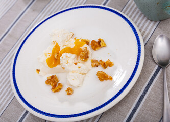Delicious farm cottage cheese with honey and walnuts on a plate