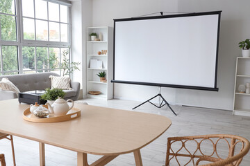 Interior of light room with projector screen and dining table