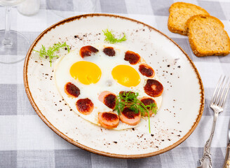 Spicy grilled sausages garnished with scrambled eggs fried closeup