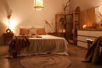 Interior of dark bedroom with cozy bed, glowing candles and lamps