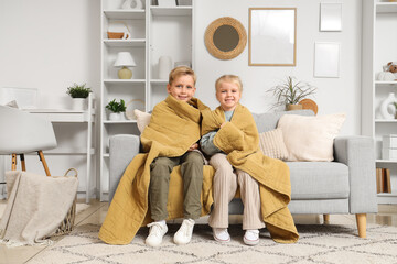 Obraz premium Kids with plaid sitting on sofa at home