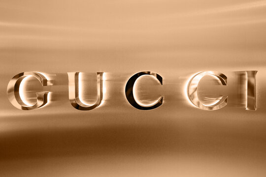 Milan, Italy - 15.12.2020: Gucci boutique exterior sign, italian luxury brand of fashion goods and leather goods. Illuminated Gucci logo of apparel store showcase. Fashion district in Milan