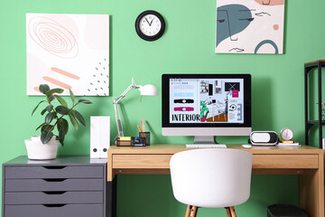 Interior designer's office with computer monitor and VR glasses near green wall in office