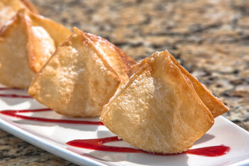 Crispy wontons filled with cream cheese and blackberry, accompanied by red fruit sauce, dessert, food