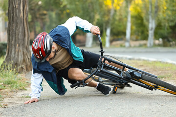Young man getting up after falling off his bike outdoors
