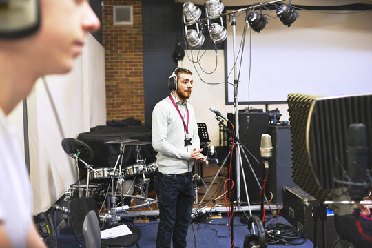 Musician, recording studio and people listening with headphones to audio, sound and production. Music, industry or performance collaboration on song for album or singer with happiness and creativity