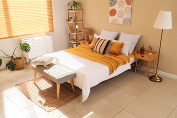 Interior of stylish bedroom with cozy bed and grey bedside bench