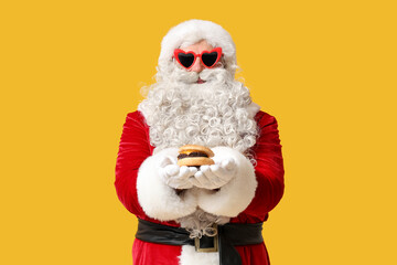 Santa Claus with tasty burger on yellow background
