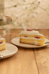 ケーキスタンドにのった苺のホールショートケーキと白いお皿に置かれたカットされたショートケーキ