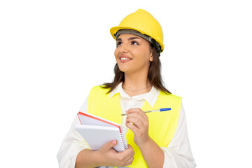 Young architect wearing safety helmet and vest holding notebook and pen, taking notes and looking...