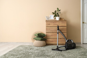 Interior of room with vacuum cleaner, commode and pouf