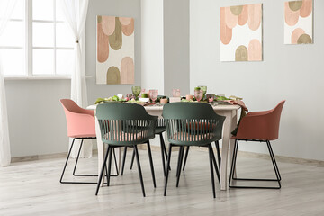 Elegant table setting with beautiful flowers and green leaves in light dining room