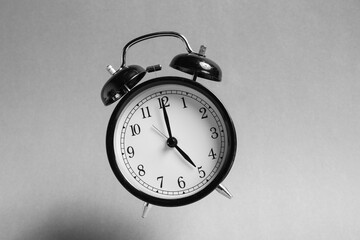 Black alarm clock in air on light grey background
