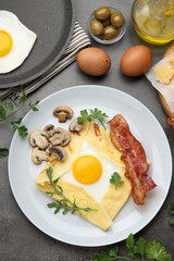 Delicious crepe bretonne with bacon, mushrooms and arugula served on grey table, flat lay