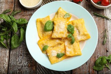 Delicious ravioli with cheese and basil served on wooden table, flat lay