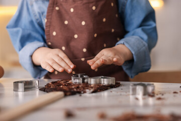 Cooking recipe. Little girl cutting cookies with cutters at table in kitchen, closeup