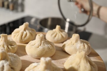 Woman with many uncooked khinkali in kitchen, closeup