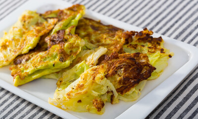 Delicious turnovers of cabbage in batter served on white plate..