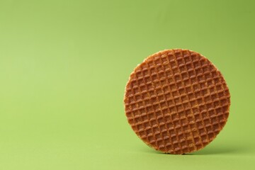 One tasty round waffle on green background. Space for text