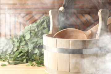 Sauna equipment. Bucket, ladle and whisk on wooden surface in steam